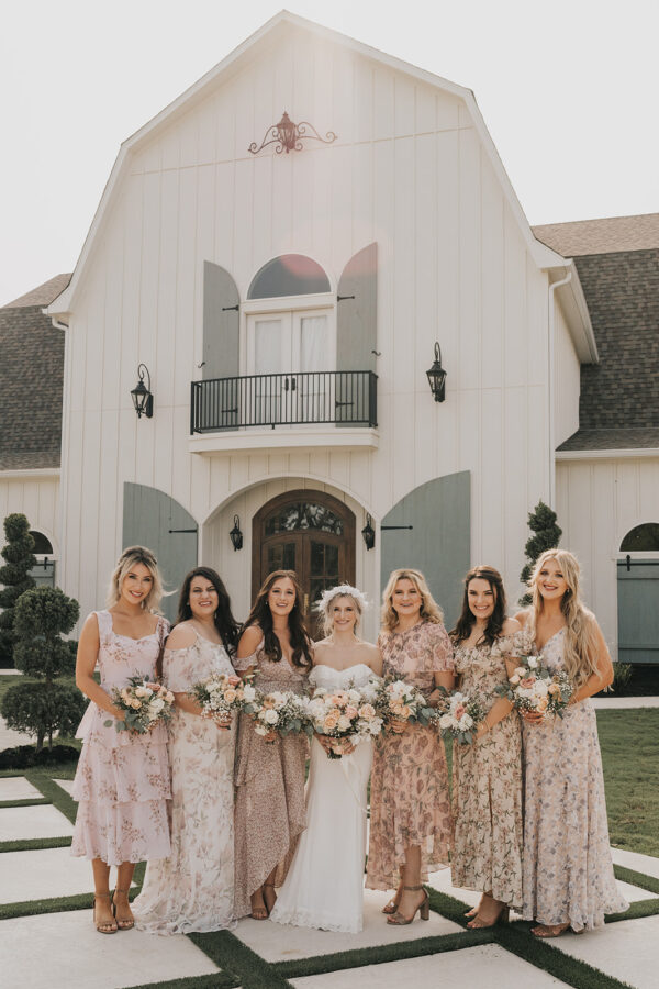 bride and her girls pose in front of the French farmhouse in their gorgeous dresses