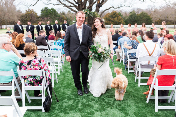 bride and groom walking down the aisle with couples dog