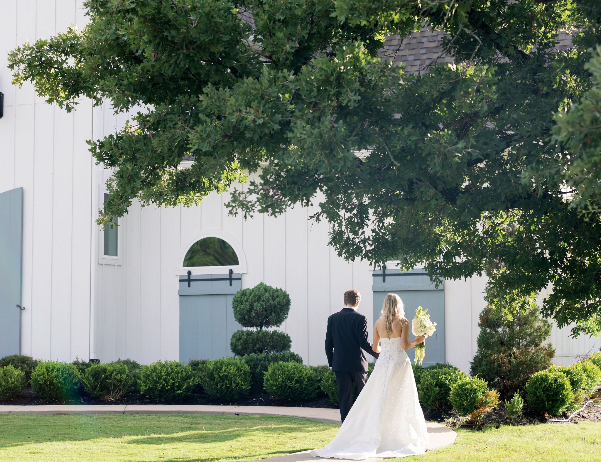 Caroline and Jacob walking hand in hand toward The French Farmhouse Venue