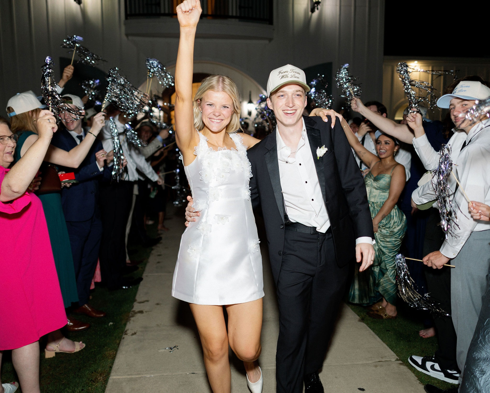 Caroline and Jacob grand exit with guests waving silver pom poms
