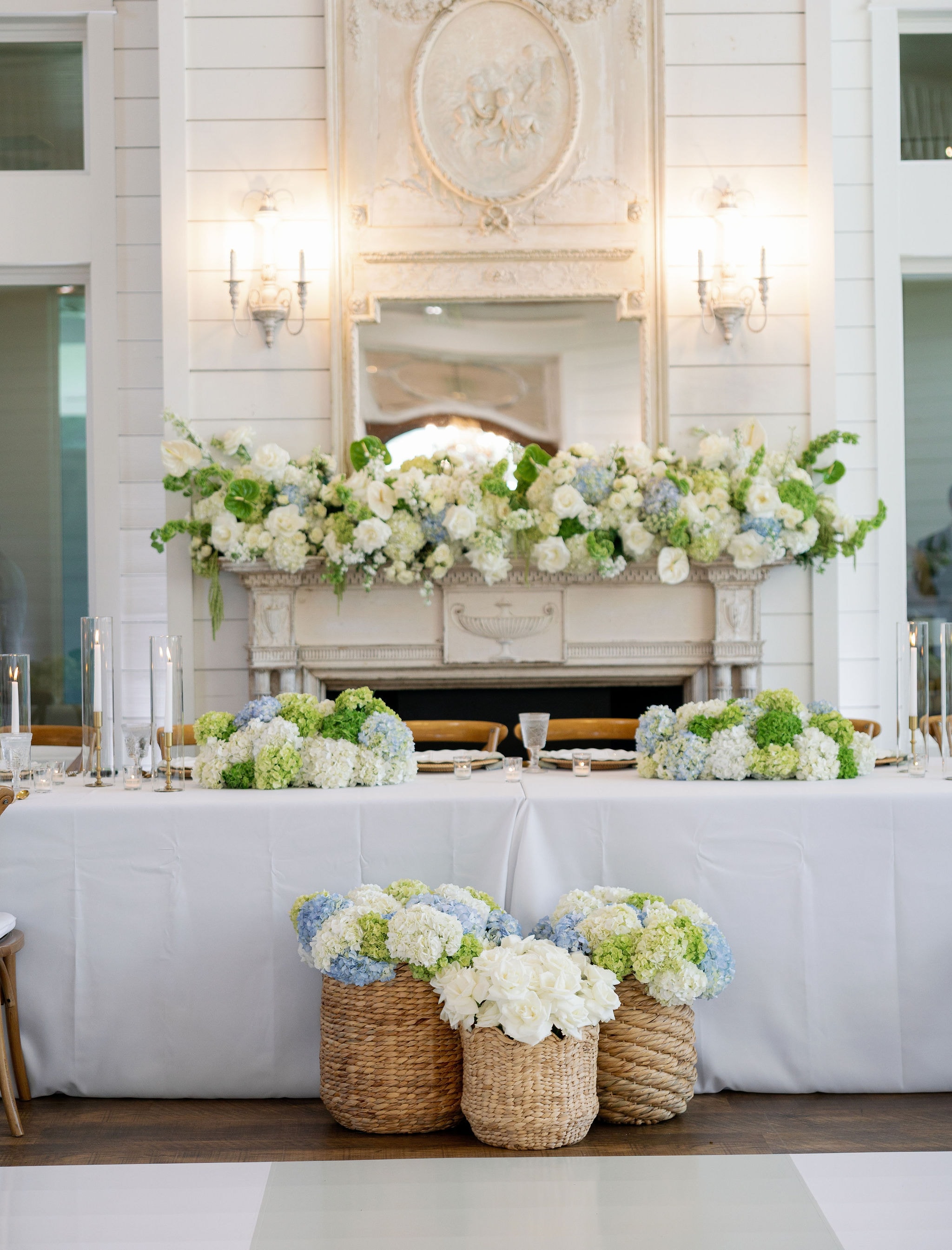 Reception head table with lush blue, white, and green hydrangea florals over the mantle