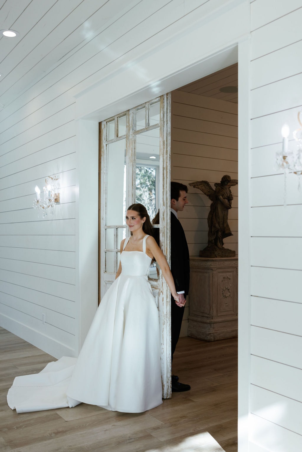 Film portrait of Brooke in her structured white ballgown leaning against the antique French doors, Shepard's hand reaching through to hold hers, the warm grain and tones of film capturing the quiet intimacy of the moment