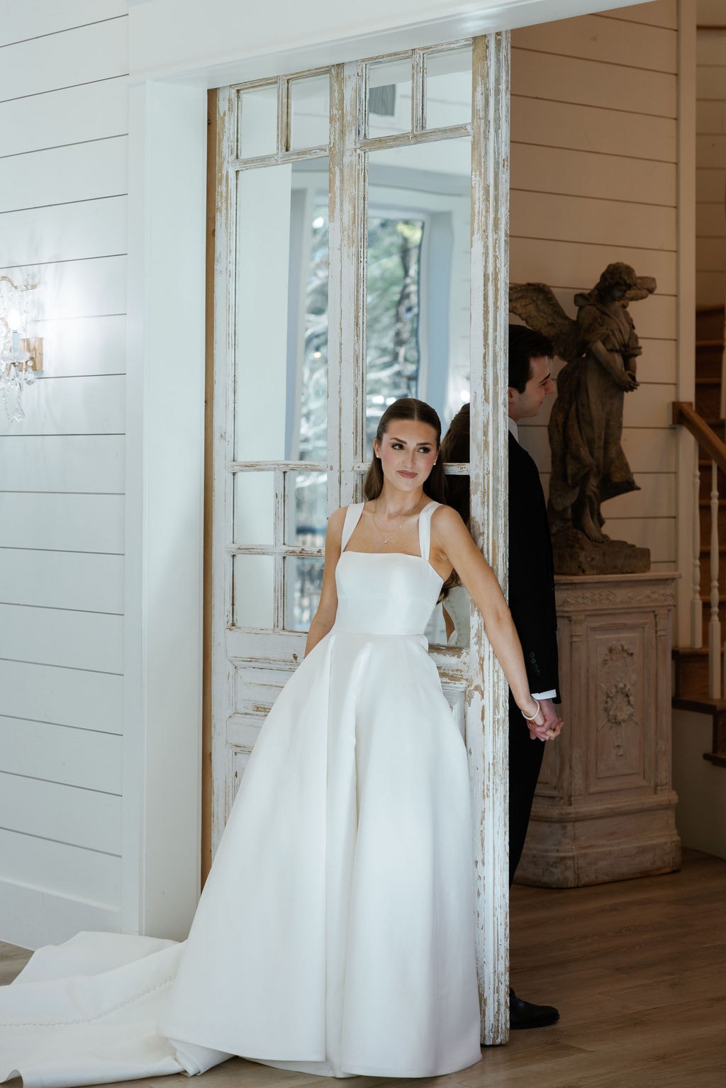 Film photo of six bridesmaids in ice blue gowns walking together down the sunlit pathway in front of the white French Farmhouse barn, laughing and holding their bouquets