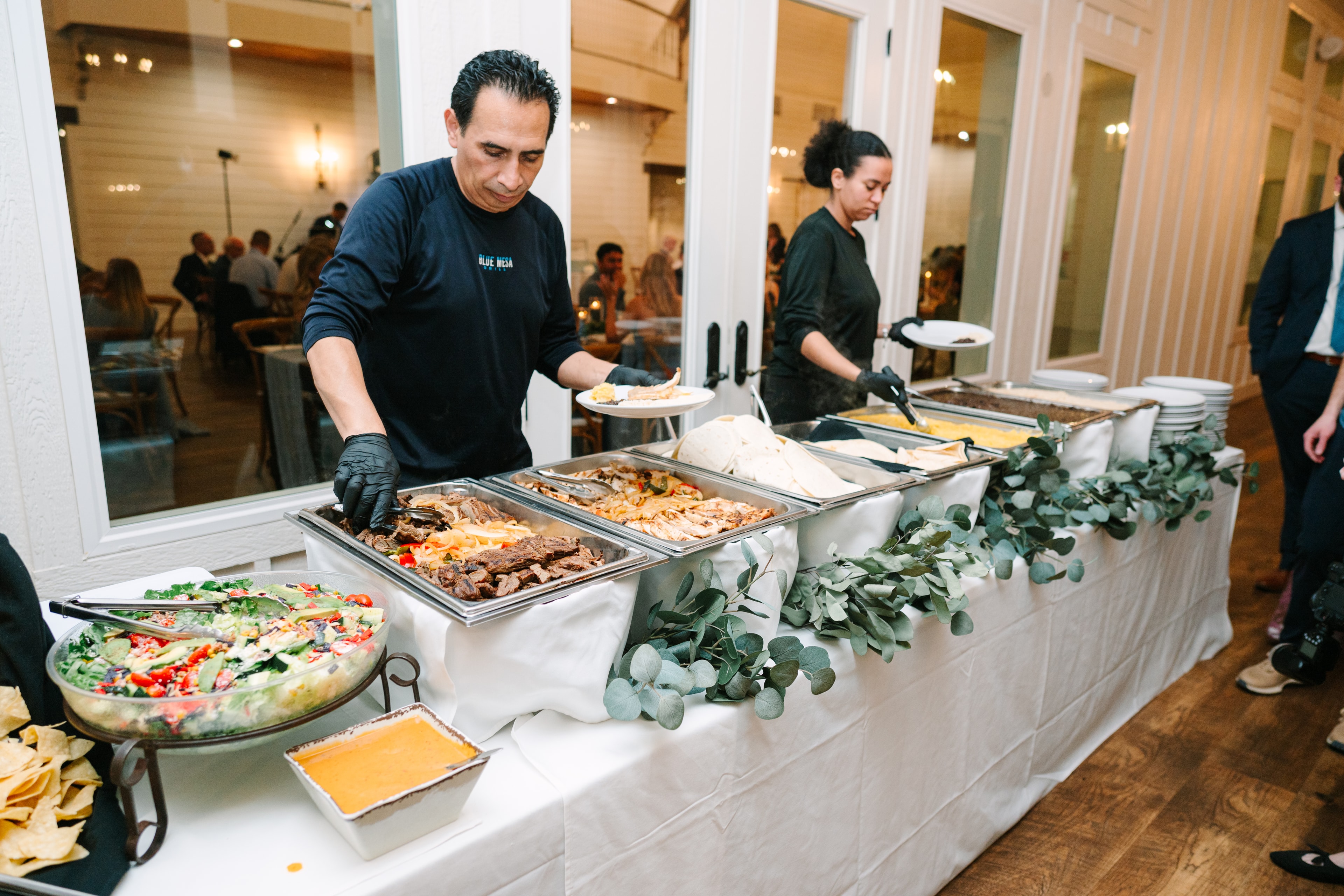 Blue Mesa catering staff serving a beautiful Southwestern buffet with eucalyptus garland at The French Farmhouse Venue