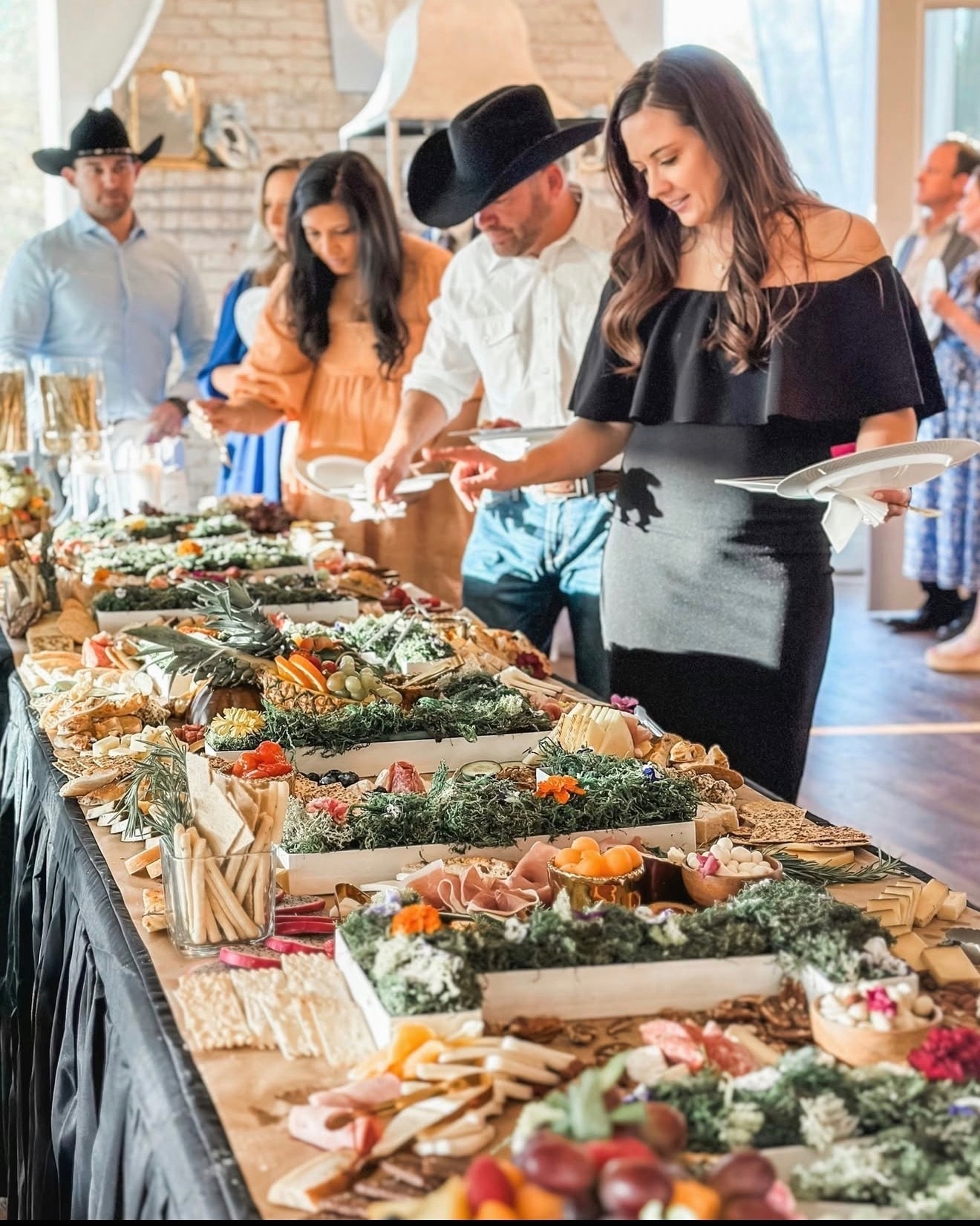 Guests serving themselves from an elaborate grazing table at a wedding reception