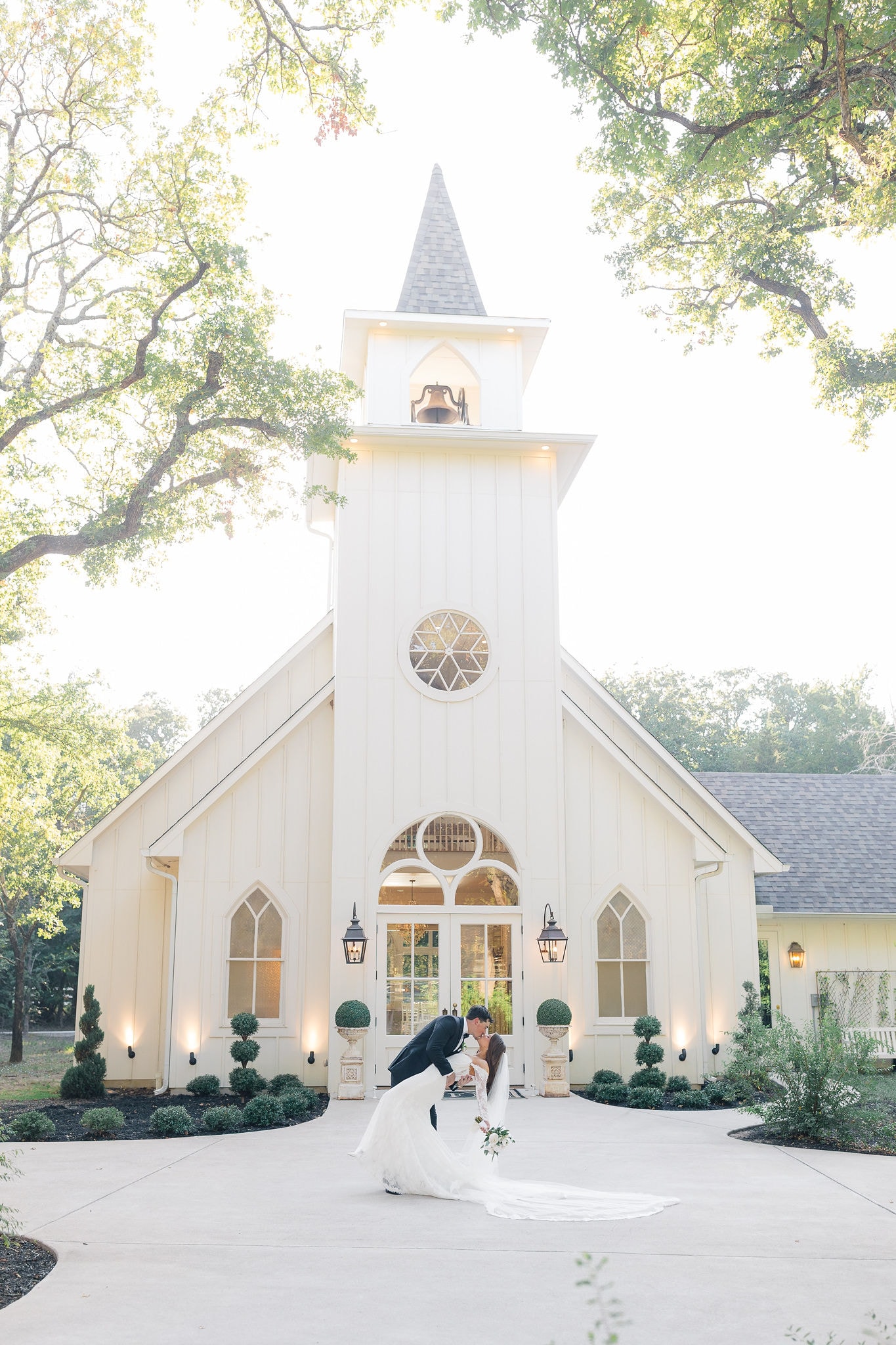 Kade dipping Catherine for a kiss in front of The French Farmhouse chapel at golden hour