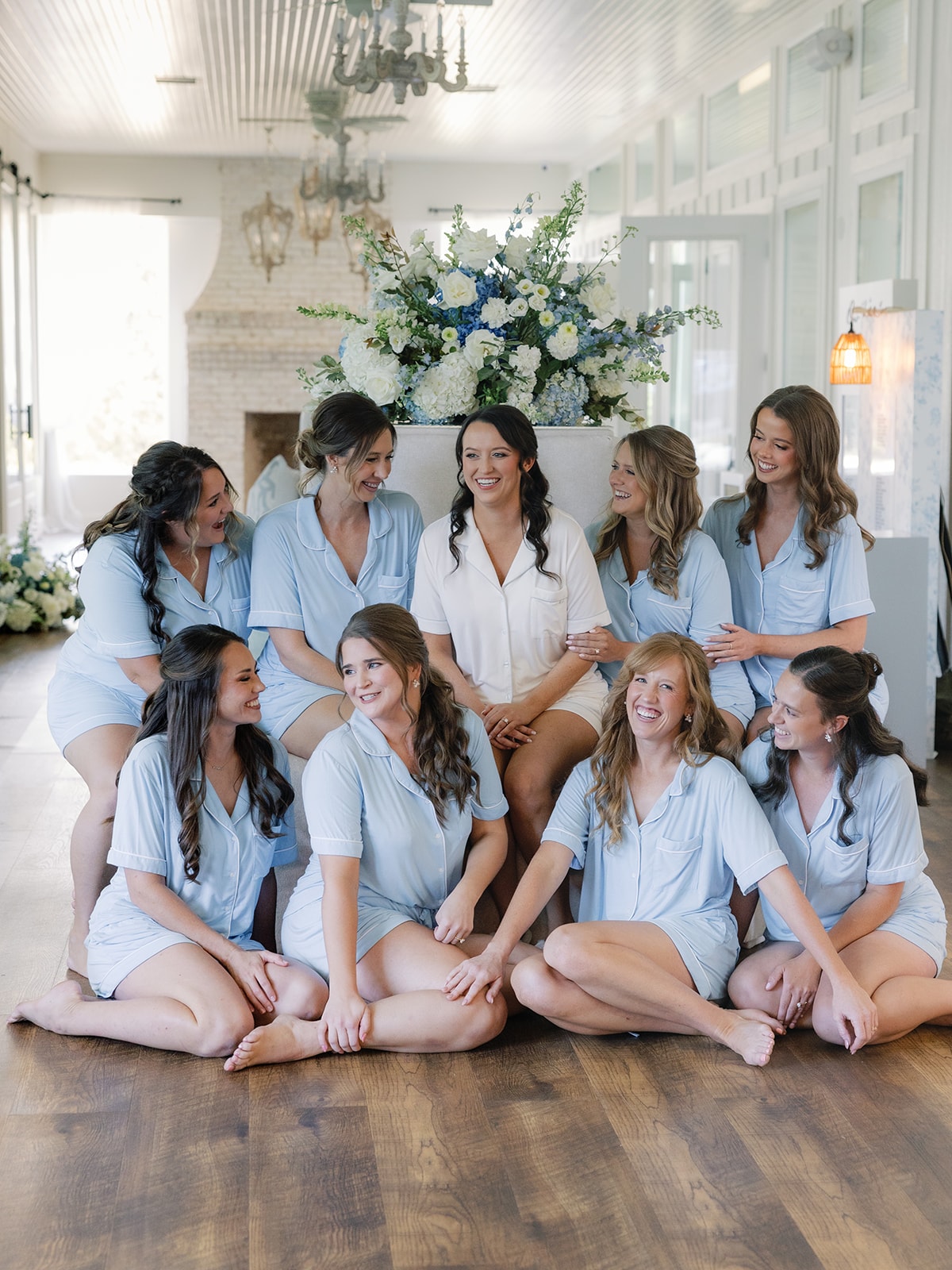 Corynn and her bridesmaids in matching light blue pajamas gathered in the bridal suite with blue and white florals