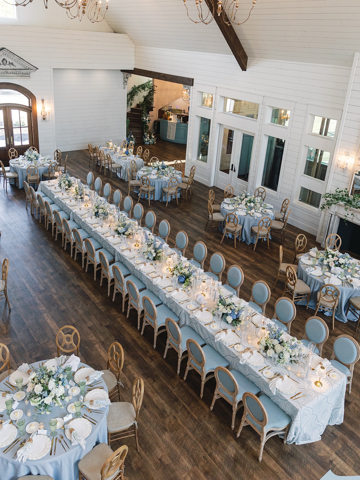Aerial view of The French Farmhouse Venue reception hall with long harvest tables and round tables in blue and white