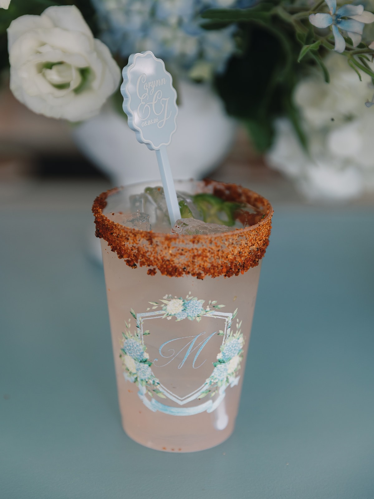 Custom monogrammed Corynn and CJ wedding cup with a spicy margarita and blue hydrangeas in the background