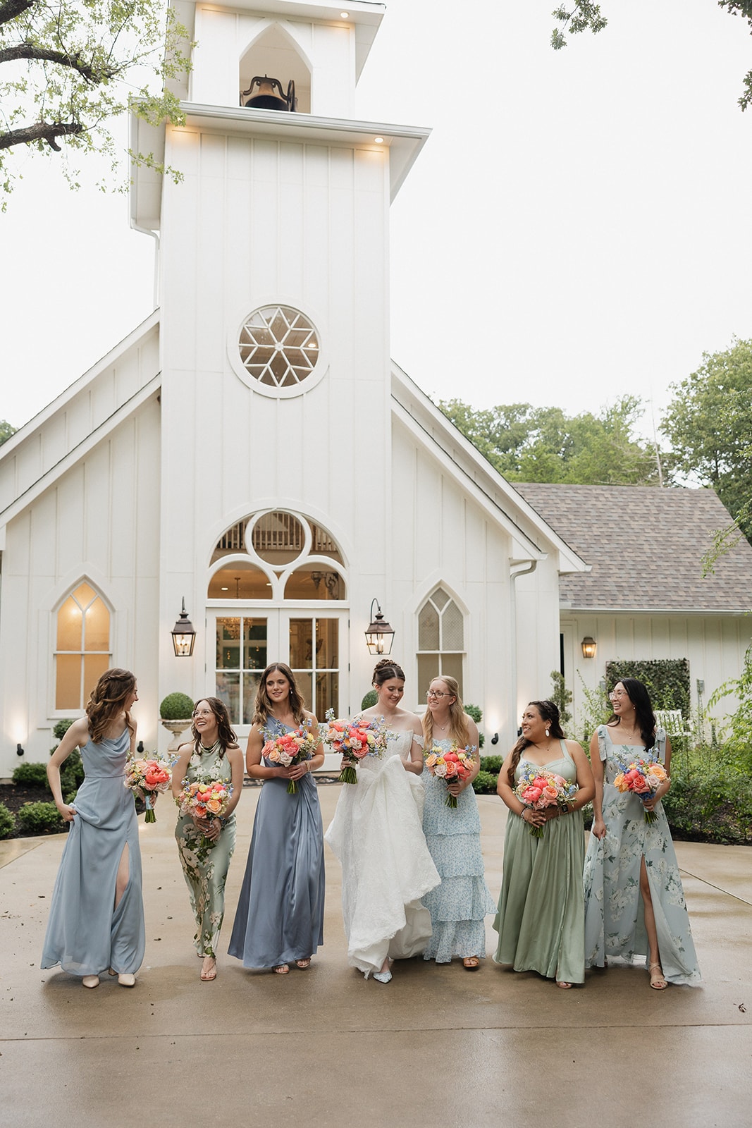 Bridesmaids in blue and green dresses in front of the chapel