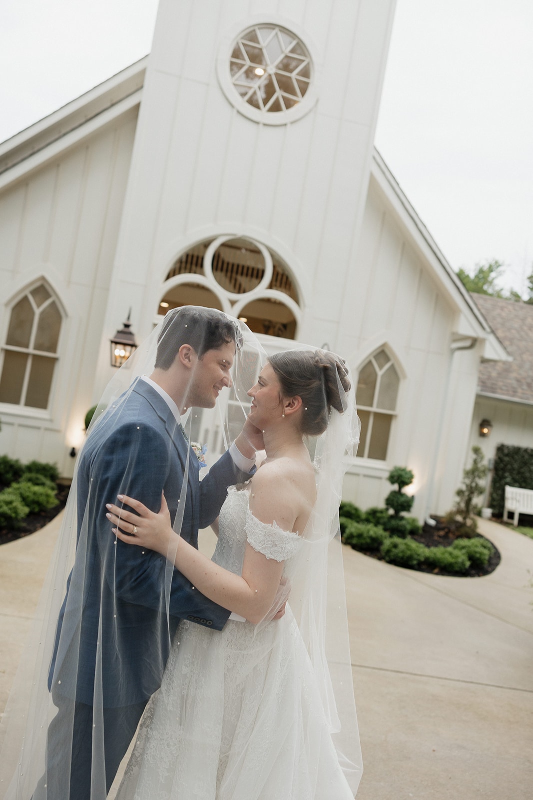 Elizabeth and Nathan under her veil in front of the chapel