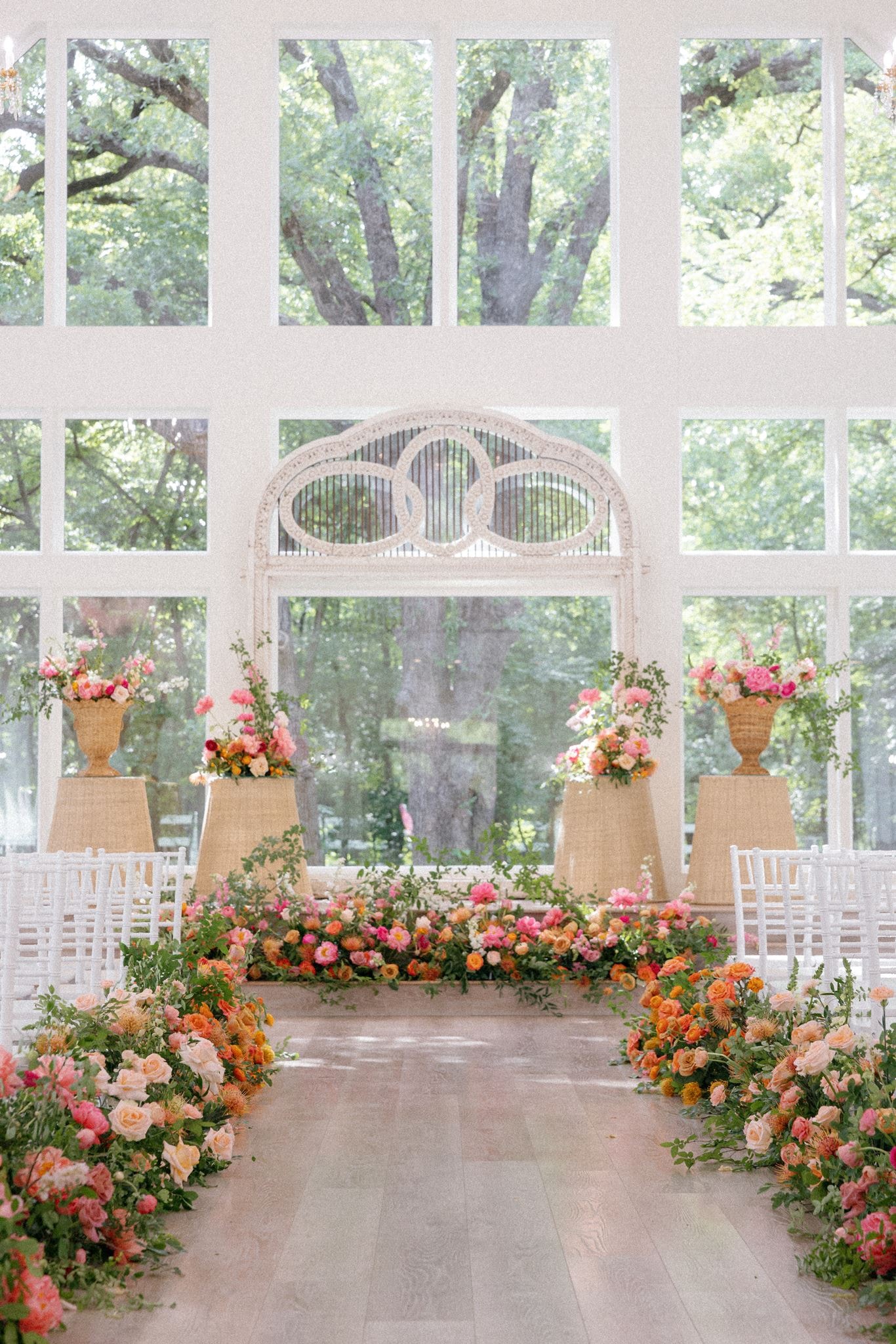 Halle and Timothy Broughton chapel ceremony setup with lush pink, orange, and coral floral aisle runners at The French Farmhouse Venue