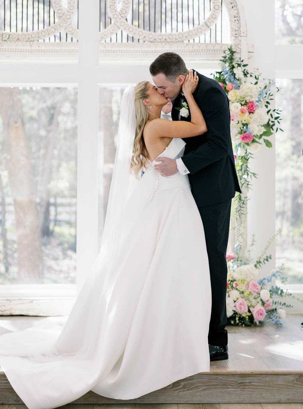 Janie and Jake sharing their first kiss as husband and wife at the chapel altar with colorful florals