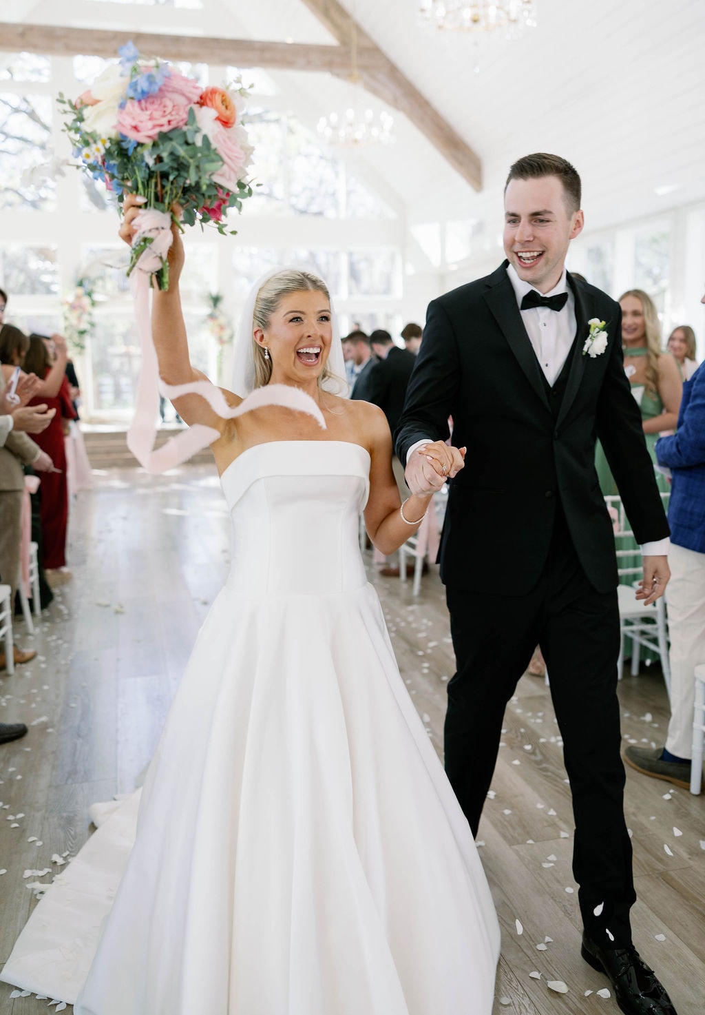 Janie raising her bouquet in celebration as she and Jake walk back down the aisle as newlyweds