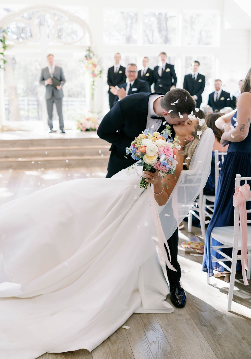 Jake dipping Janie for a kiss during the recessional with flower petals falling around them