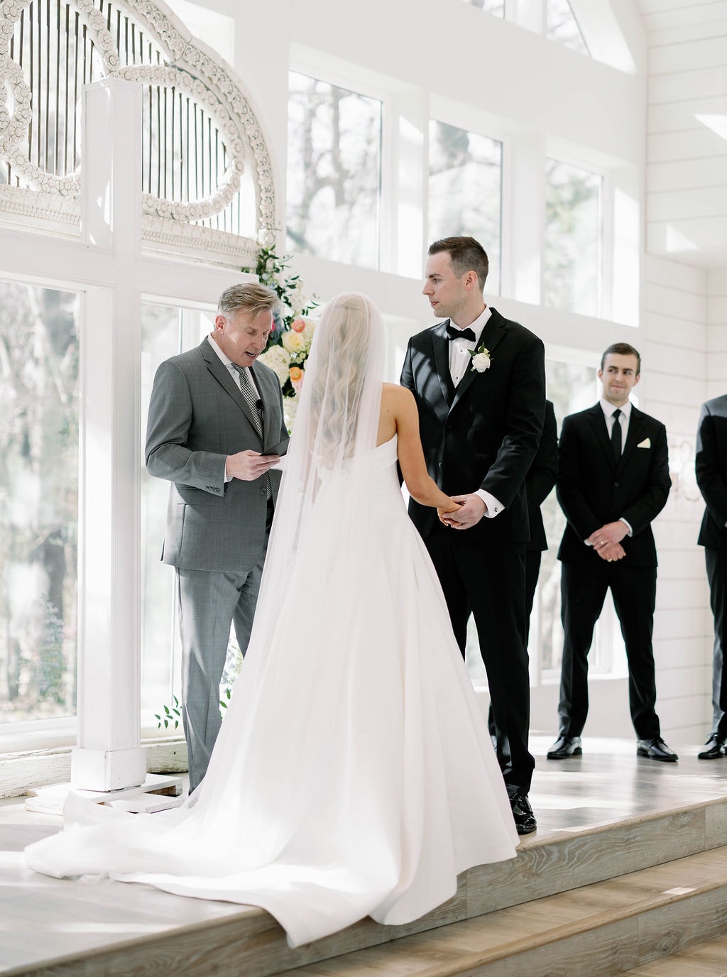 Close-up of Janie and Jake holding hands at the altar during their vows
