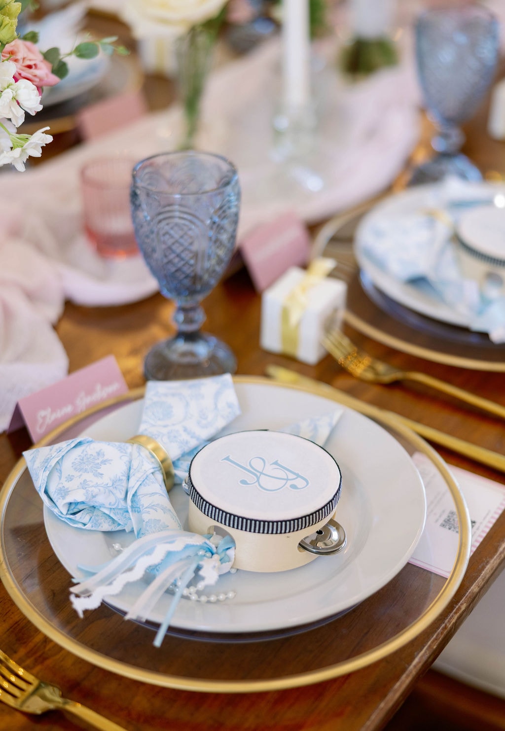 Place setting with monogrammed tambourine, blue toile napkin, and gold charger plate