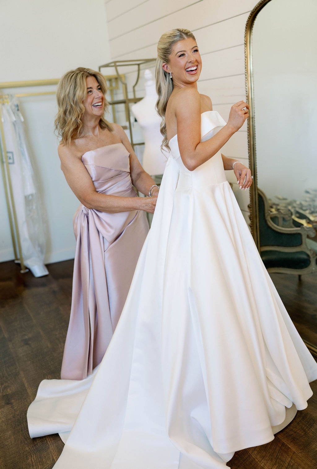 Janie's mom helping button her into her wedding gown, both laughing