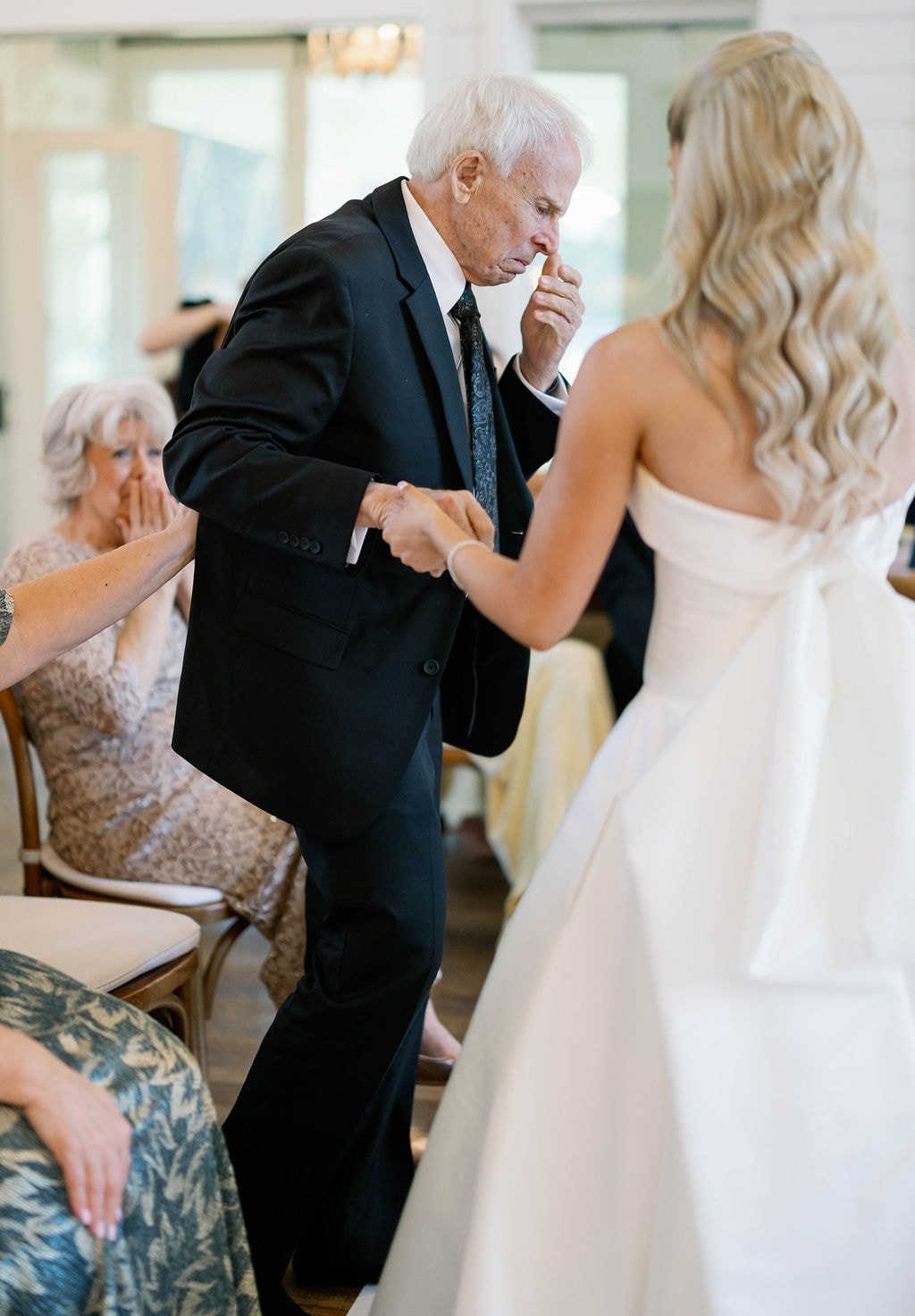 Janie dancing with her grandpa during a surprise dance at the reception while guests watch with emotion