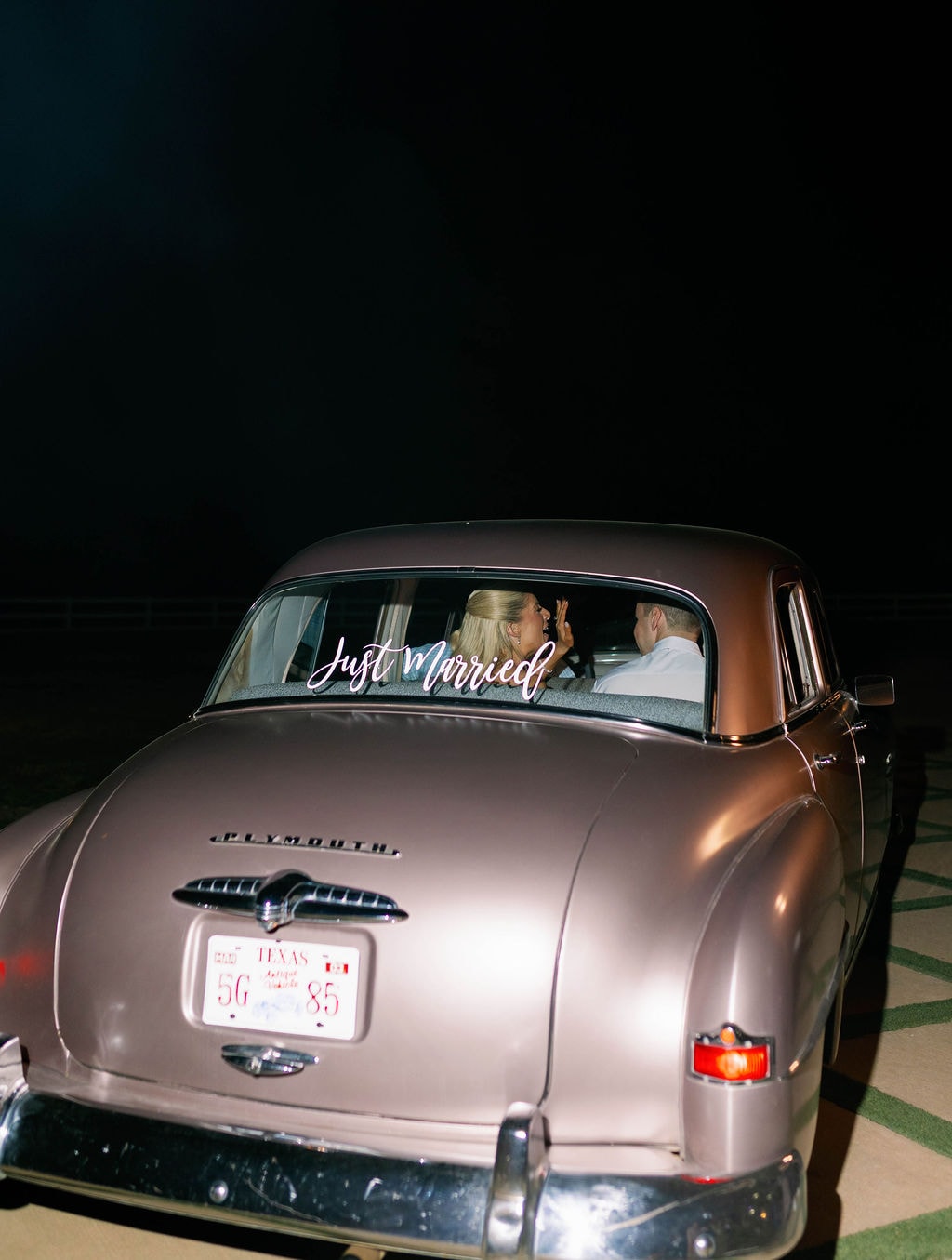 Janie and Jake driving away in a vintage Plymouth with Just Married written on the back window under the Texas night sky