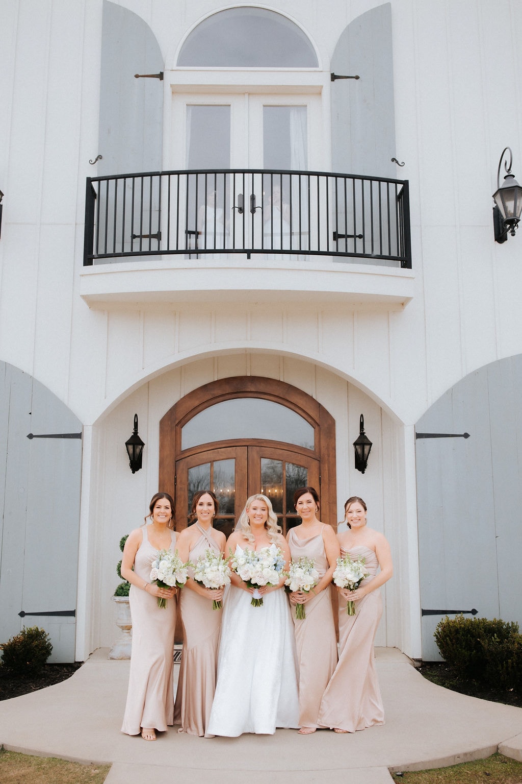 Kara with her bridesmaids in champagne dresses in front of the venue entrance