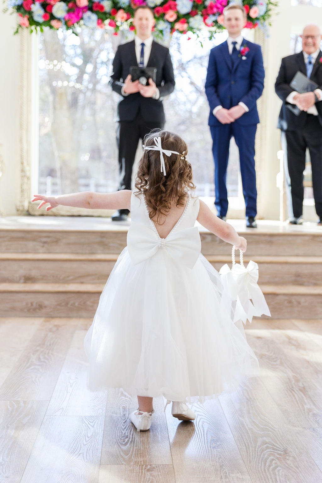 Flower girl in white dress walking down the chapel aisle toward the altar