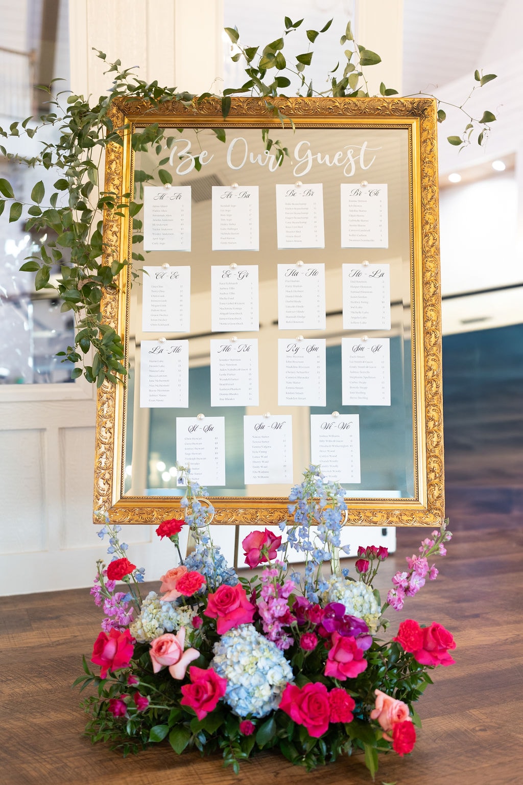 Be Our Guest gold mirror seating chart surrounded by colorful florals