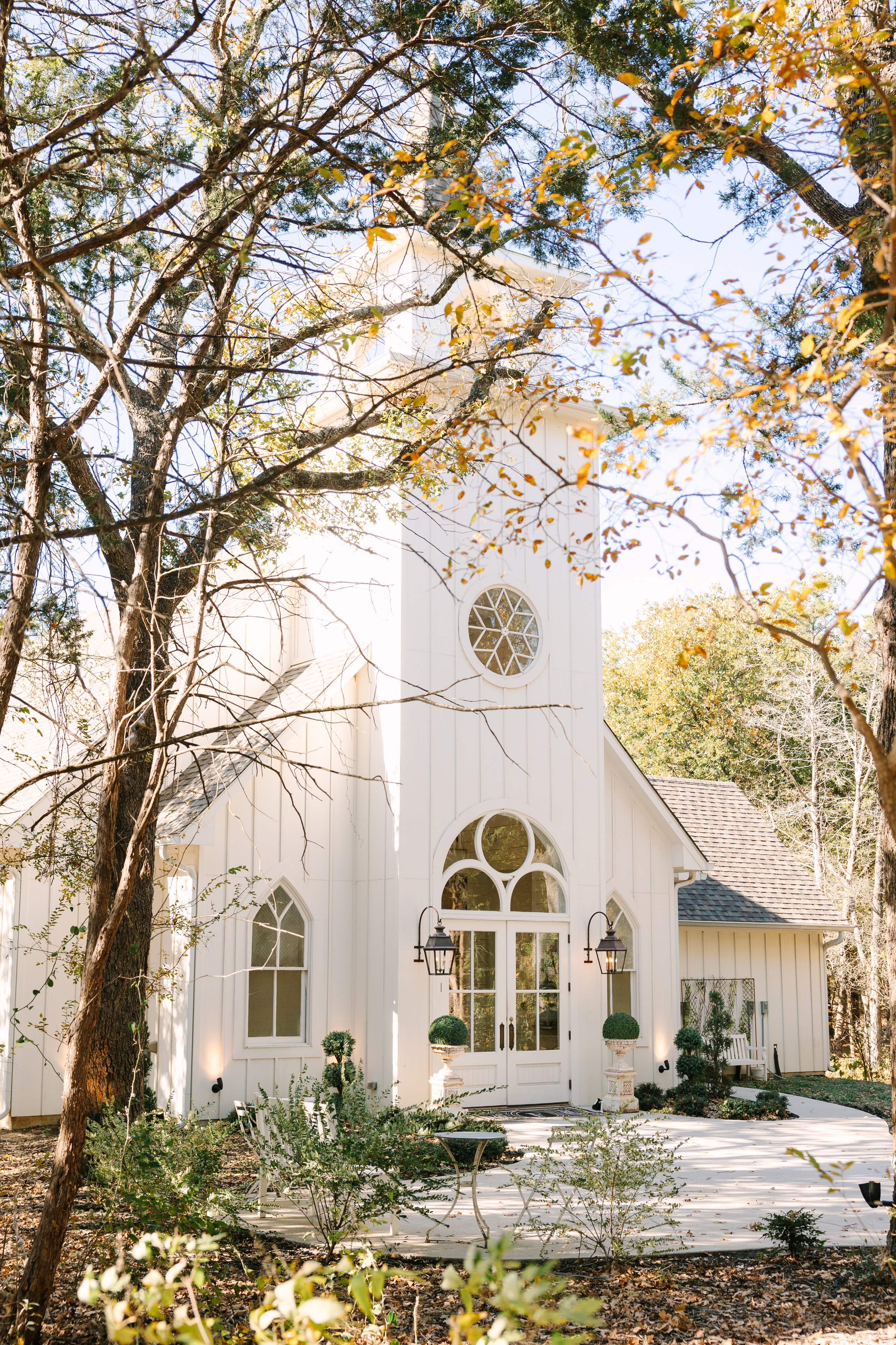 The French Farmhouse chapel exterior surrounded by golden autumn trees on Katie and Mason's November wedding day
