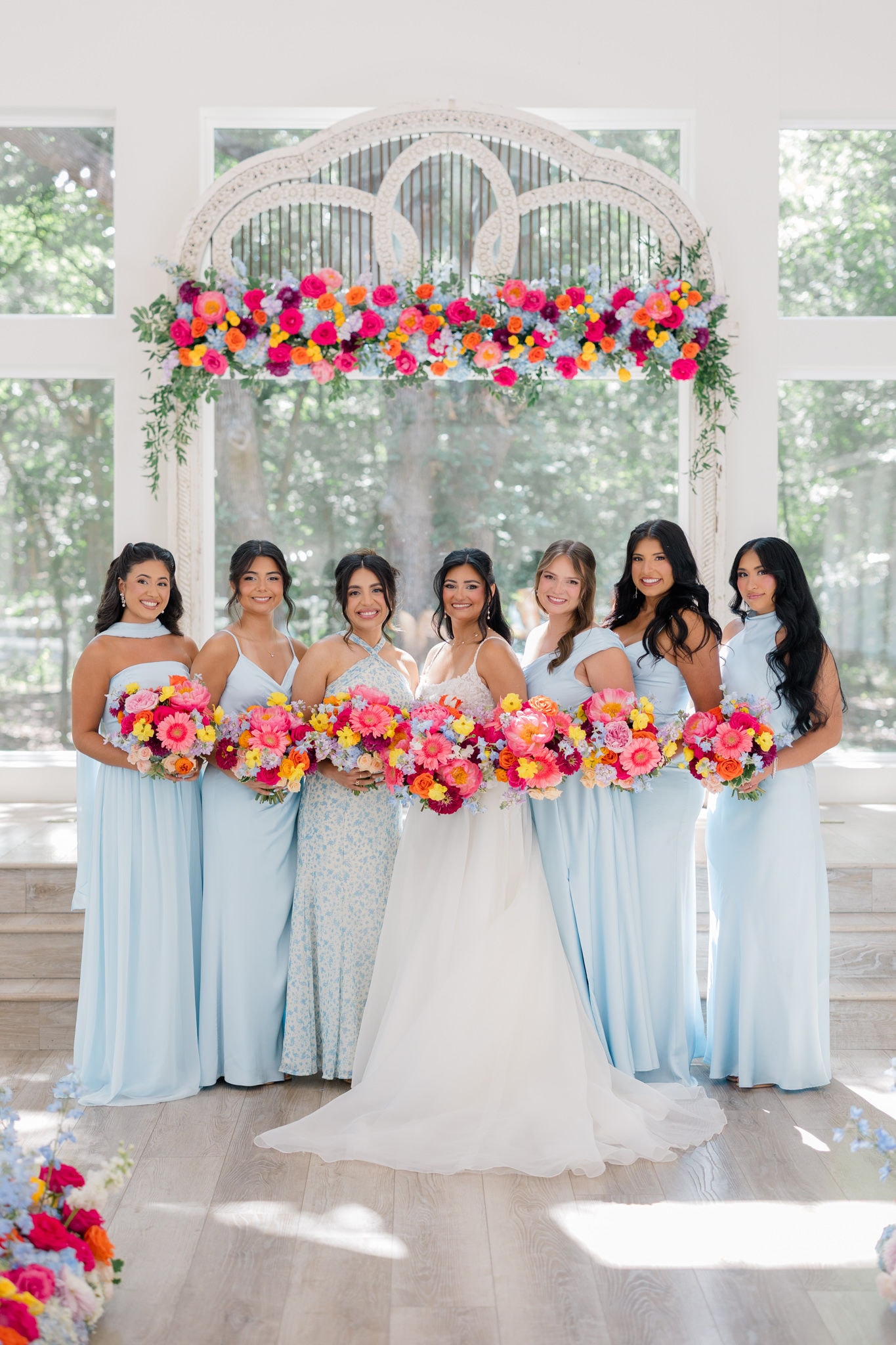 Larissa Patty with her bridesmaids holding colorful bouquets at The French Farmhouse Venue on July 10, 2026