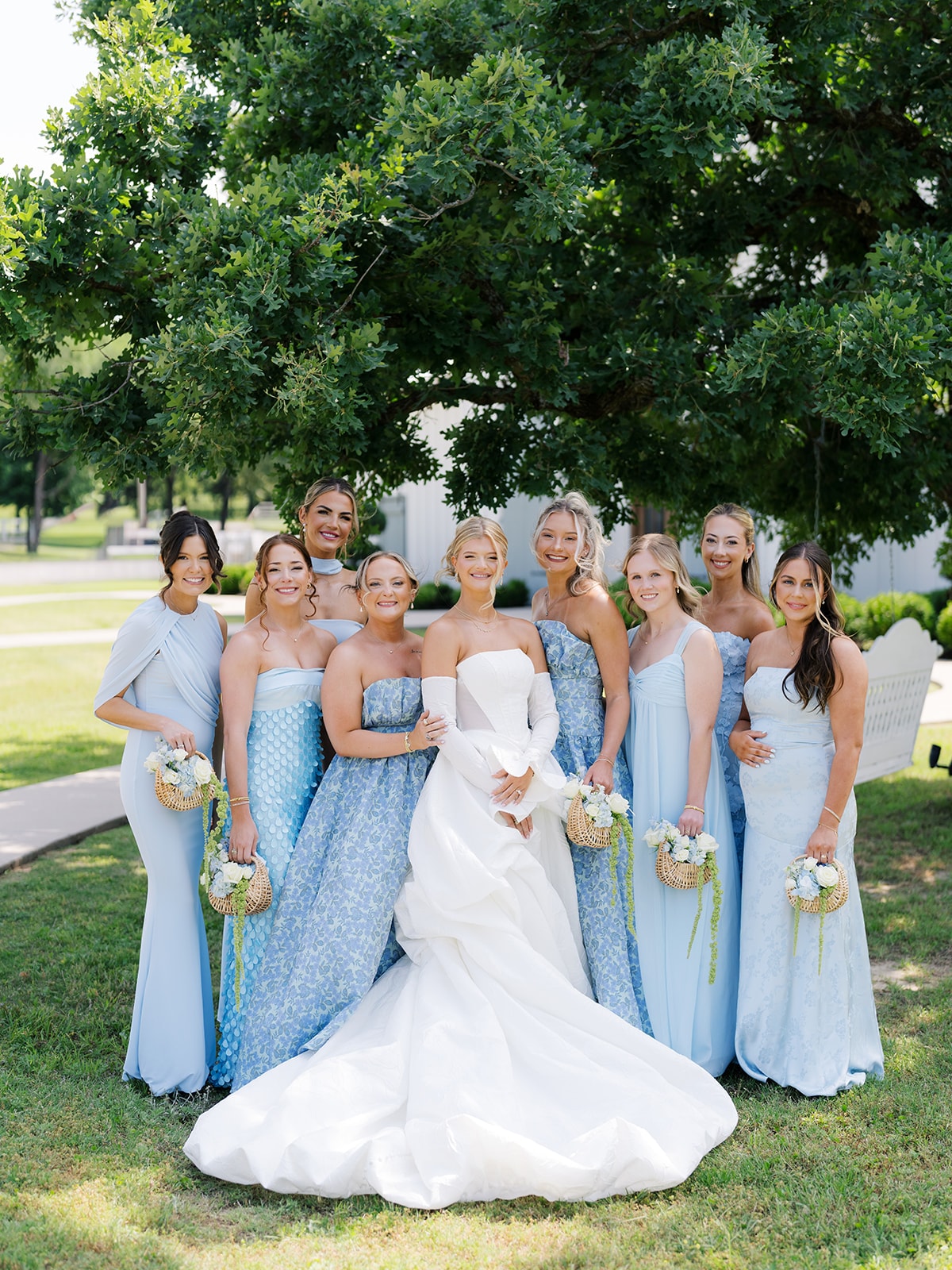 Macey and her four bridesmaids in dusty rose spaghetti-strap gowns standing together outdoors on the grounds of The French Farmhouse Venue, holding white and blush bouquets