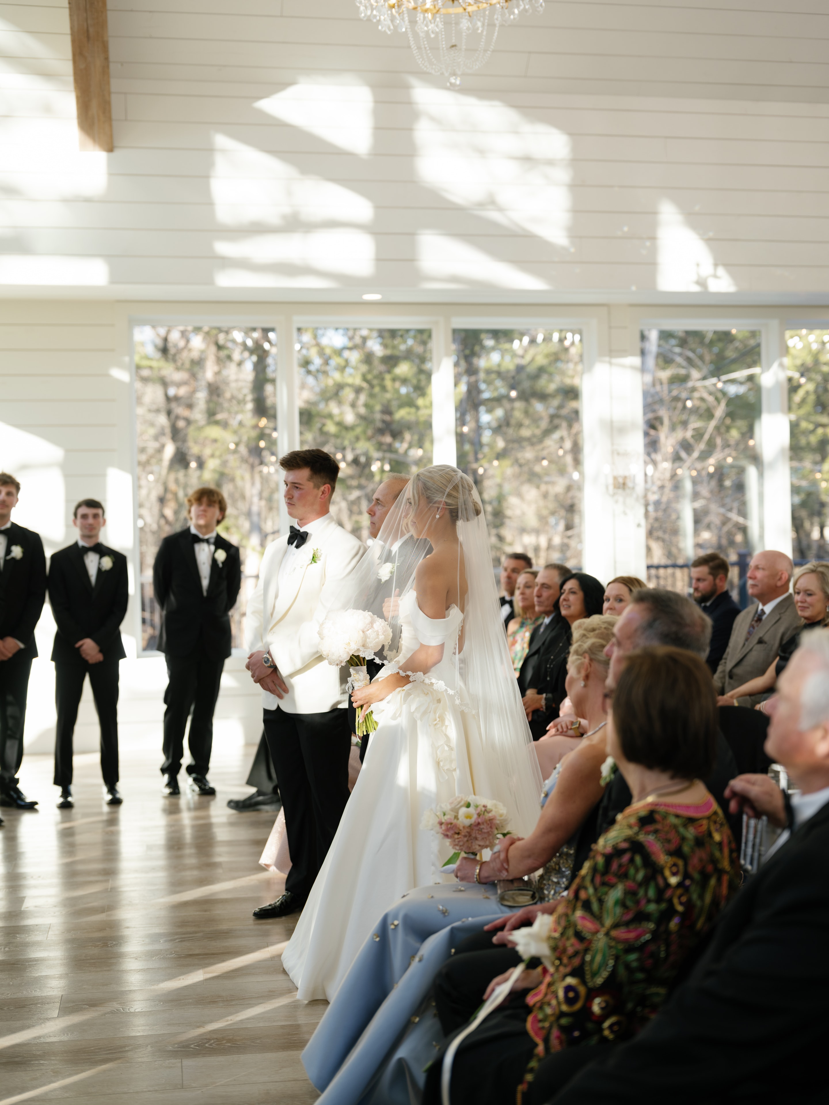 Megan and Rex at the altar with groomsmen lined up in black tuxedos at The French Farmhouse chapel