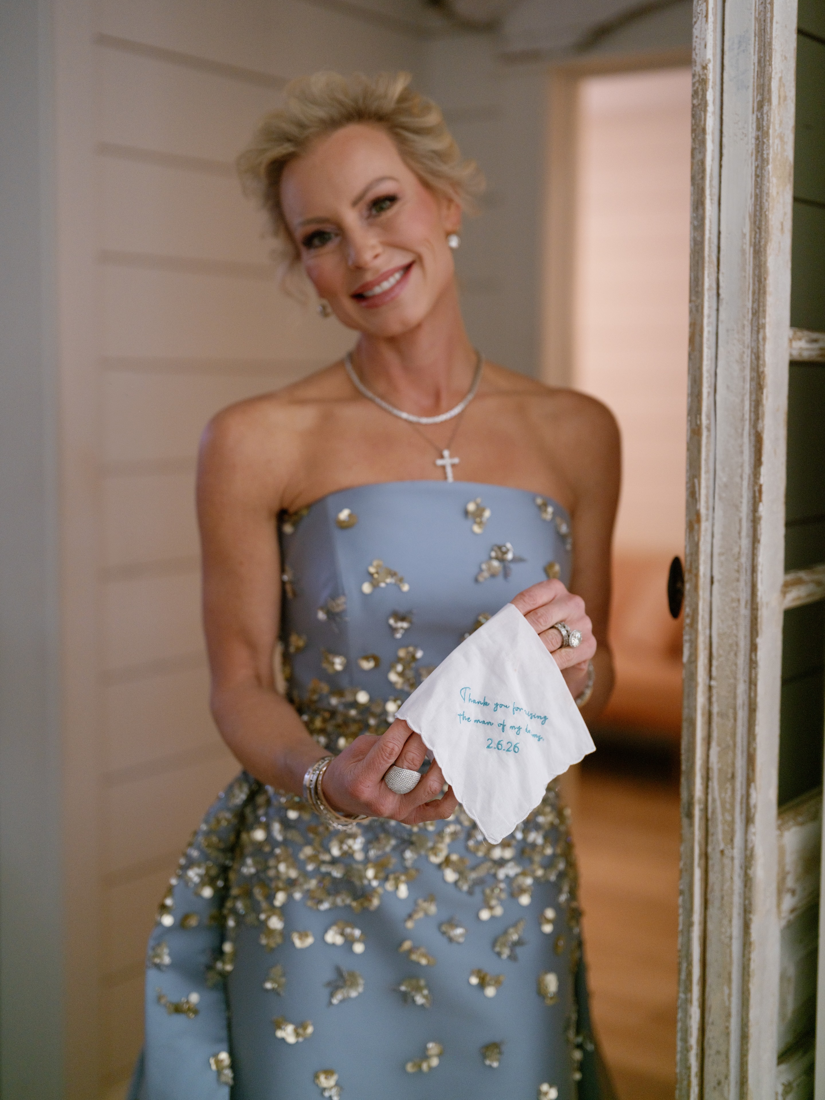 Megan in her off-the-shoulder wedding gown smiling by the bridal suite door at The French Farmhouse Venue