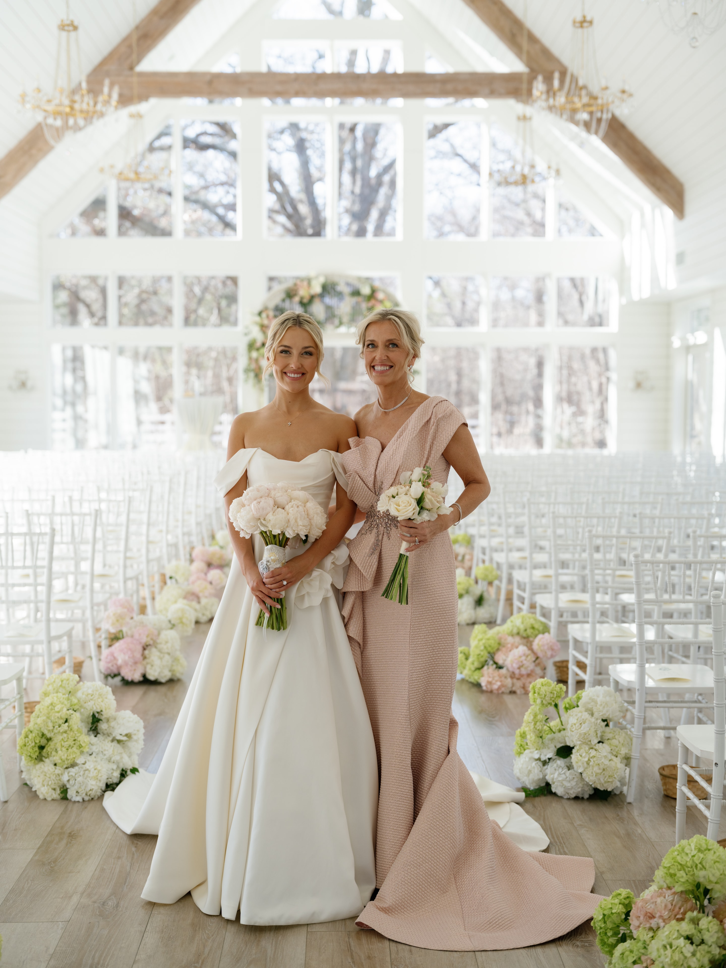 Megan and her mother standing together in the chapel before the ceremony holding bouquets