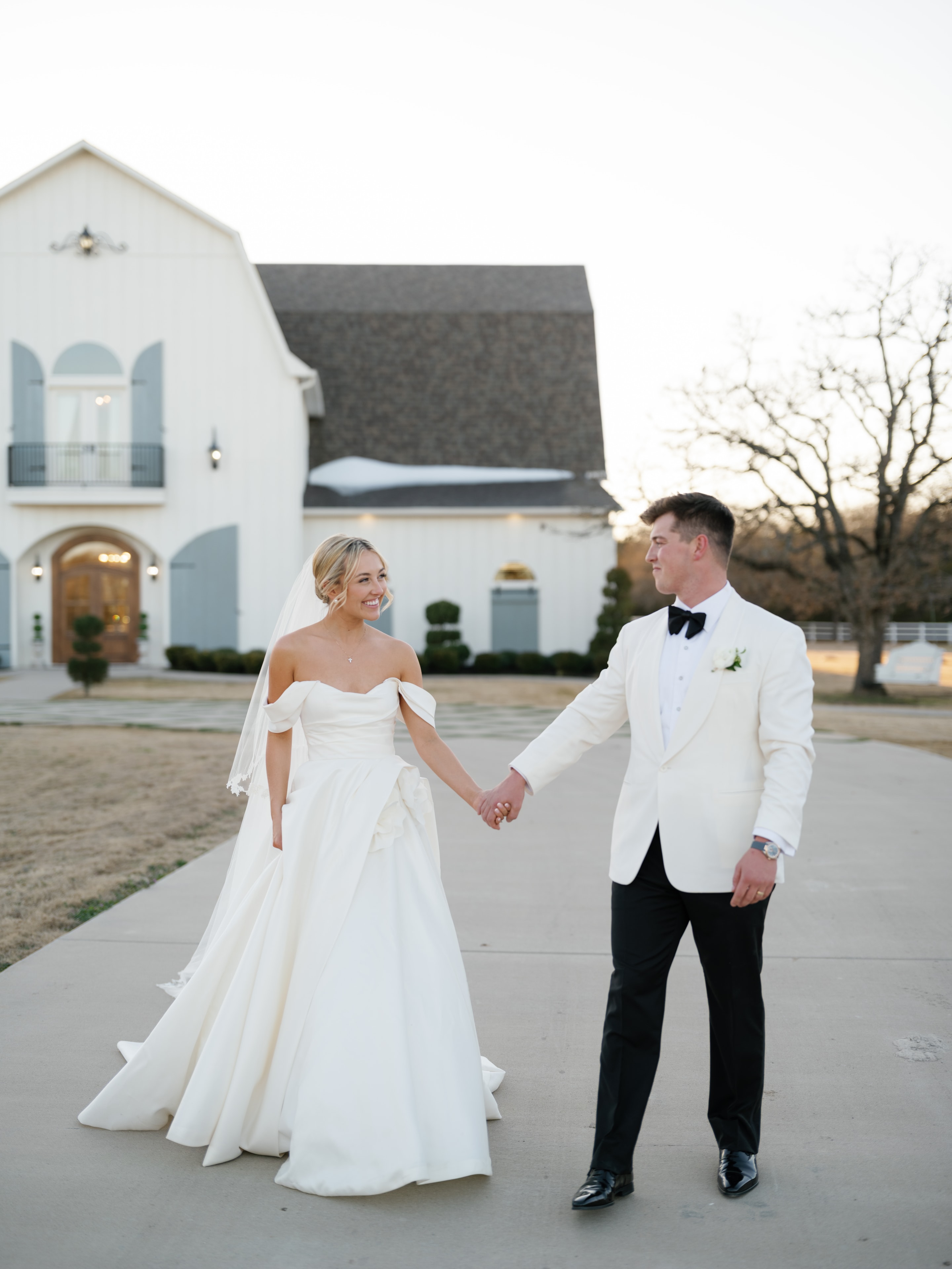 Megan and Rex holding hands in front of The French Farmhouse Venue at golden hour