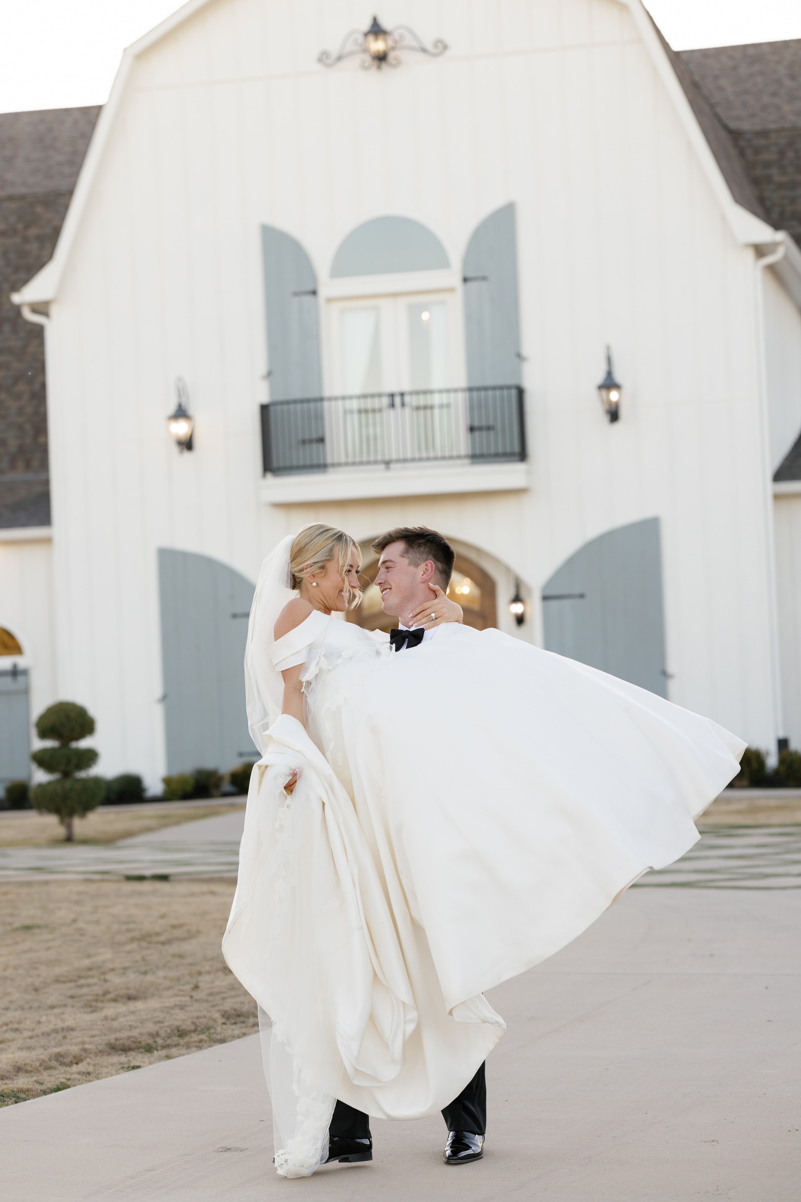 Rex lifting Megan in front of The French Farmhouse Venue on their wedding day