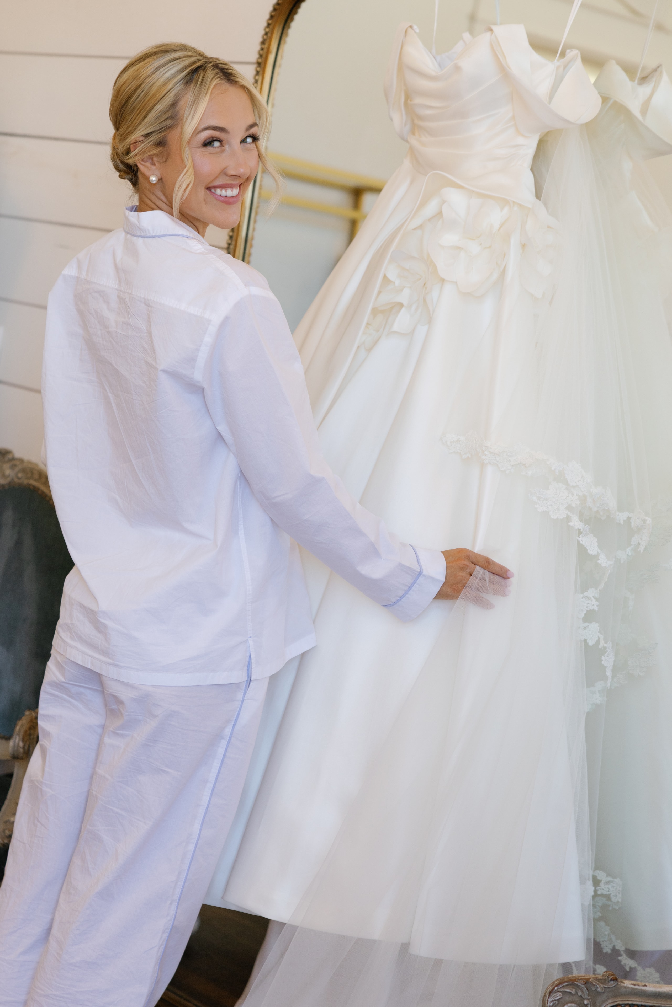 Megan and Rex laughing together as they cut their tiered white wedding cake