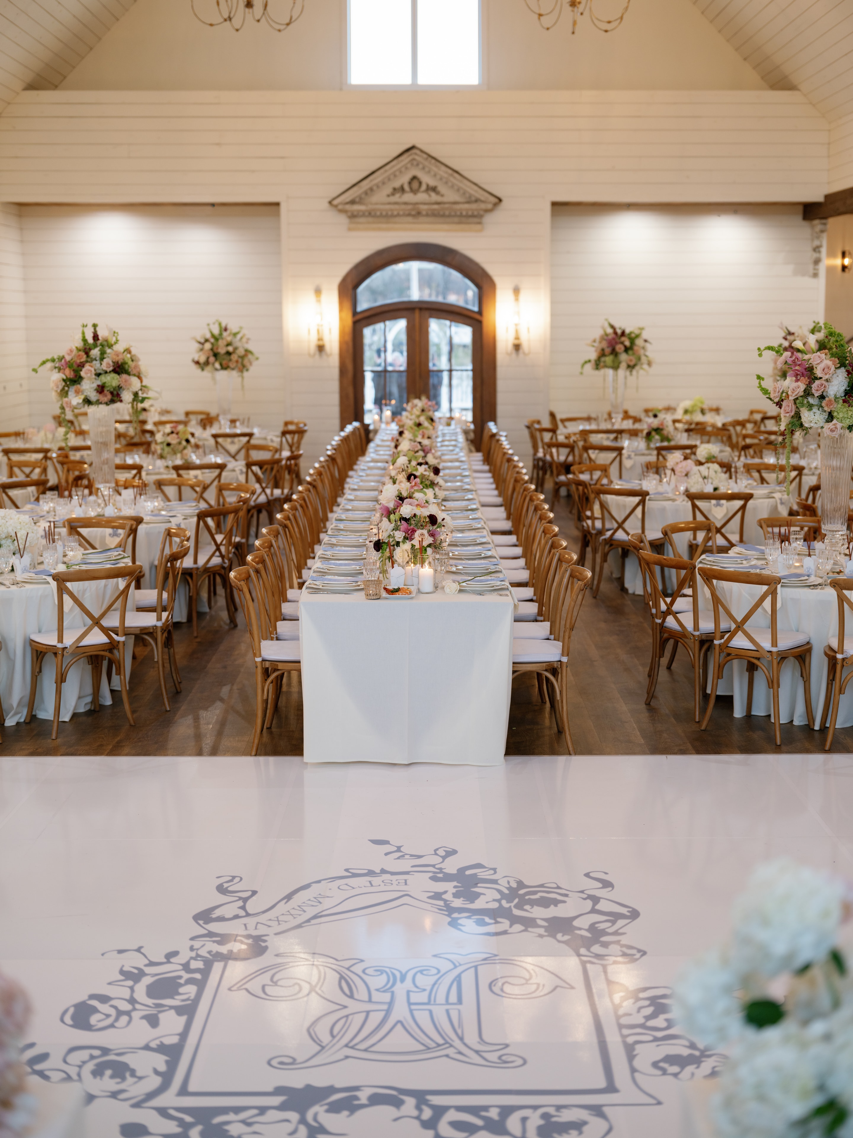 French Farmhouse reception hall with custom monogram dance floor and tall floral centerpieces