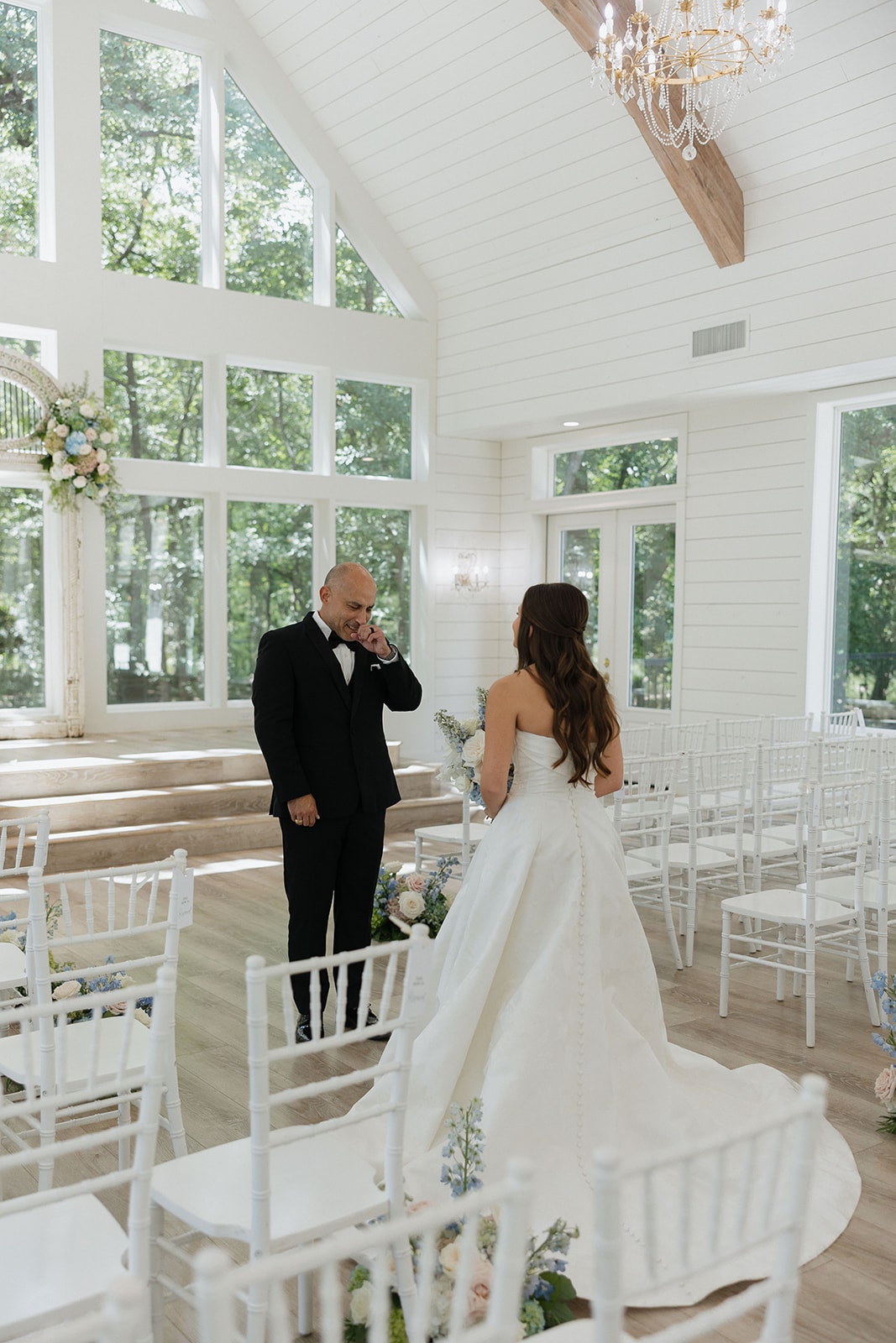 Nina's dad wiping away tears as he sees his daughter in her wedding gown for the first time inside the light-filled French Farmhouse chapel
