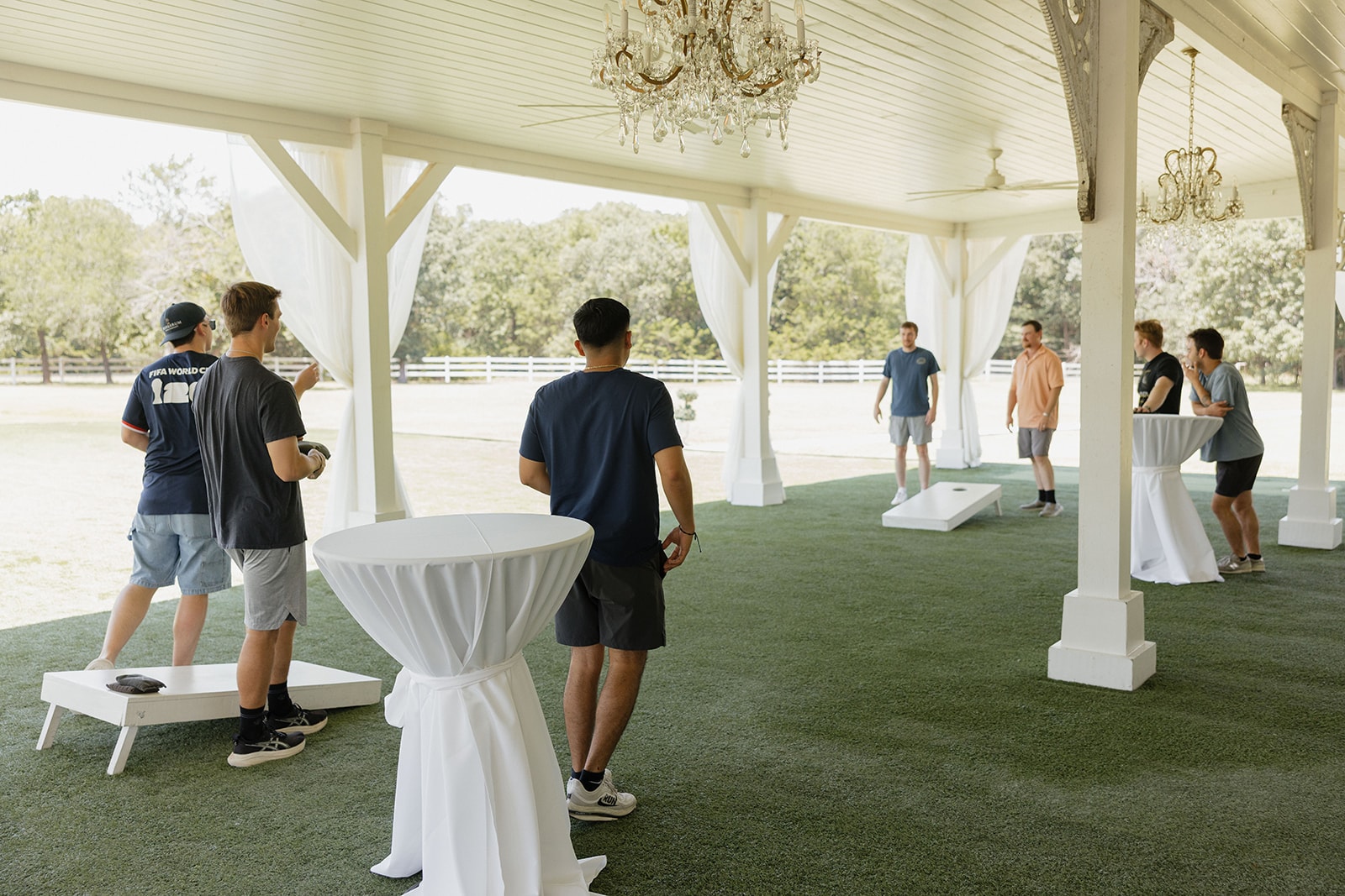 Gage's groomsmen playing cornhole under the covered outdoor pavilion at The French Farmhouse Venue on the morning of the 4th of July wedding