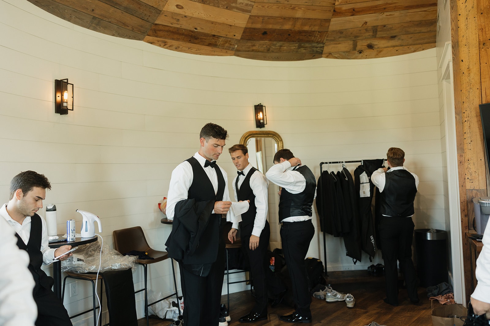Gage's groomsmen getting into their tuxedos in the groom's room at The French Farmhouse Venue on July 4th, 2026