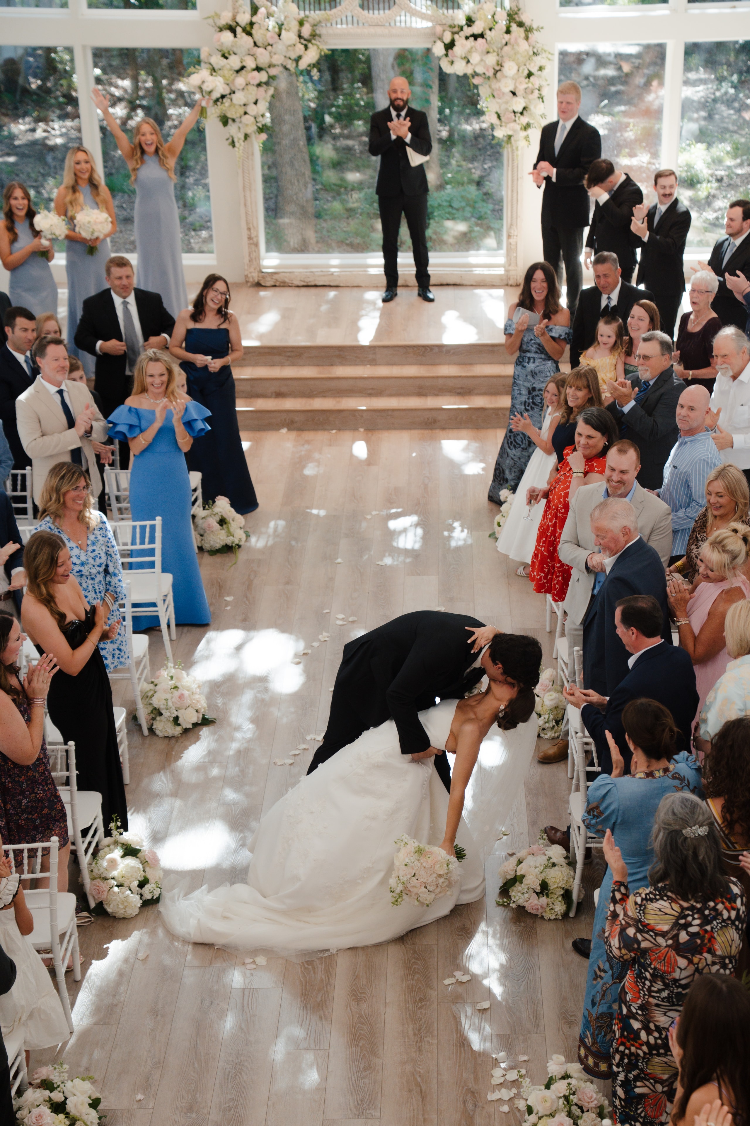 DJ dipping Paige for a kiss during their recessional as guests cheer inside The French Farmhouse chapel