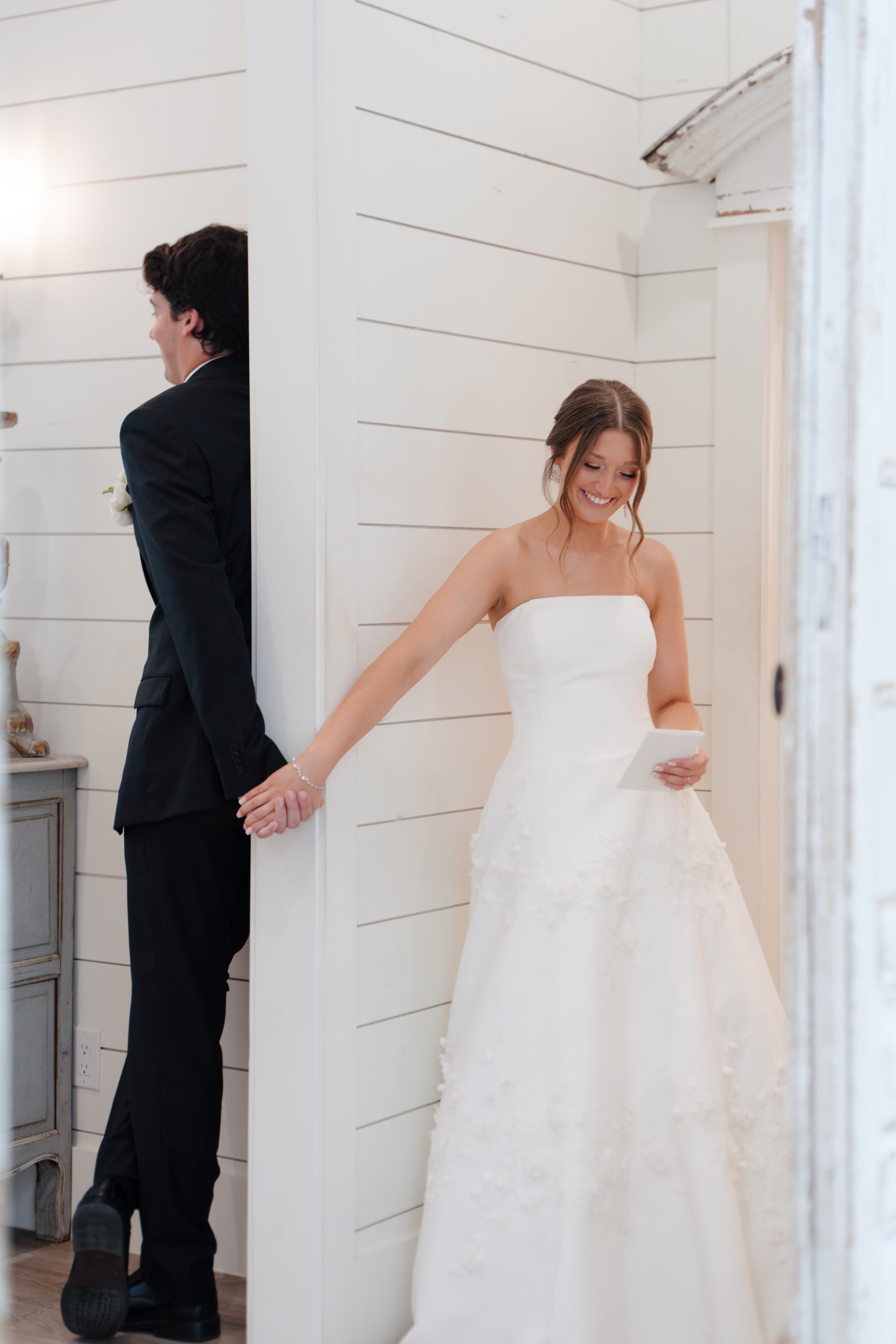 Paige and DJ sharing their first touch through the chapel wall at The French Farmhouse Venue, holding hands as Paige reads her vows
