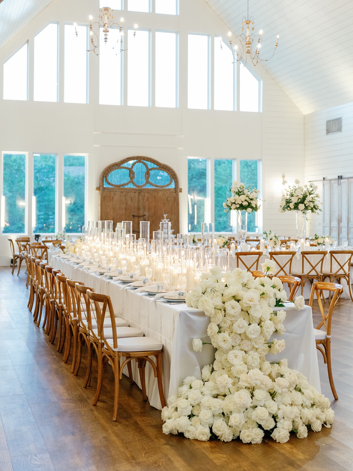 Beautiful reception table setting with white flowers and wooden chairs at The French Farmhouse Venue