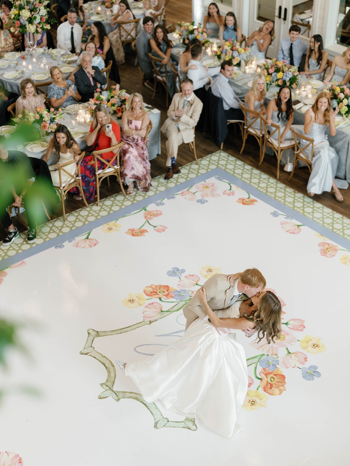 Couple sharing a romantic dip kiss on the custom painted dance floor at The French Farmhouse Venue